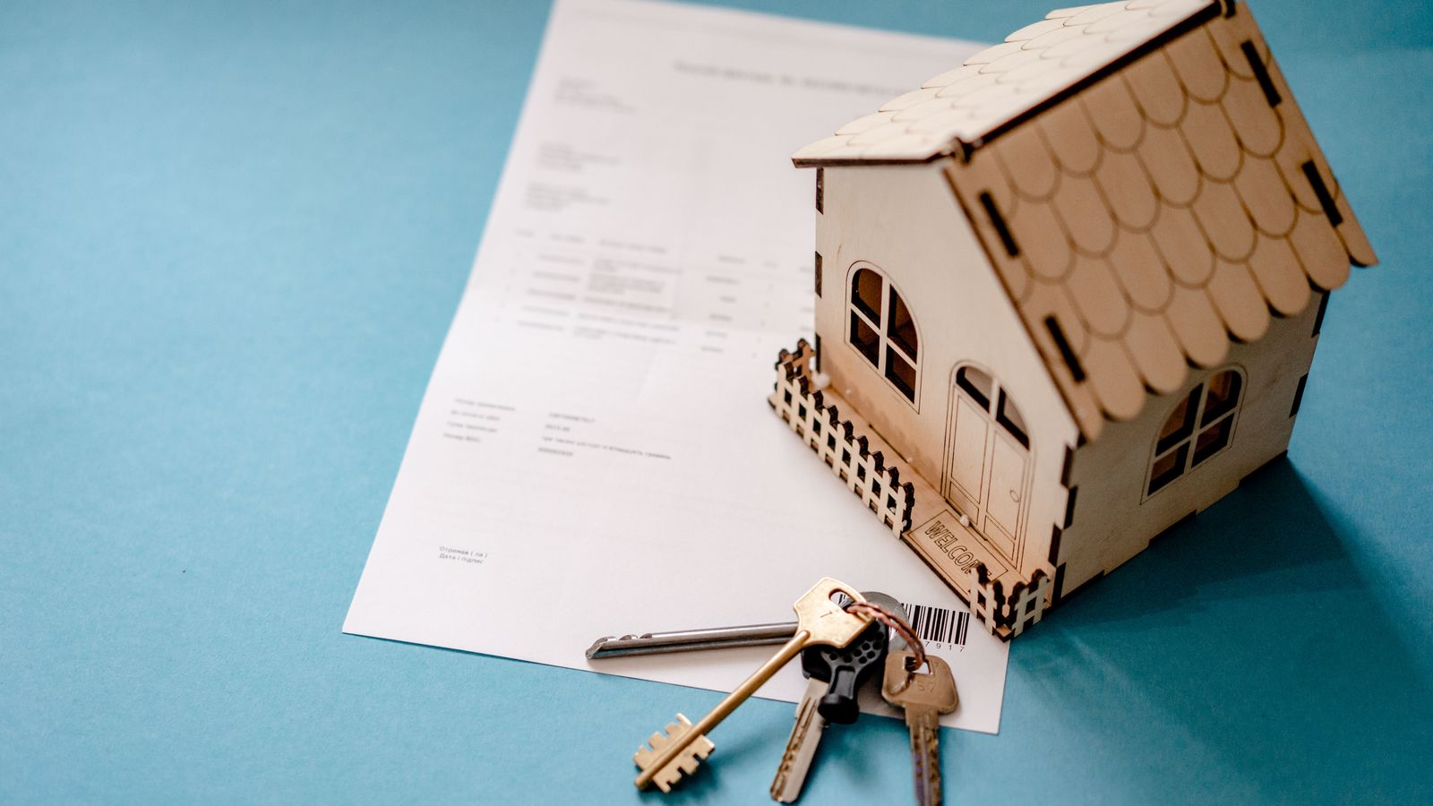 Maison miniature avec contrat de bail et clés symbolisant la révision de loyer IRL